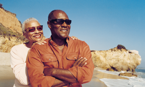 older black couple smiling on the beach