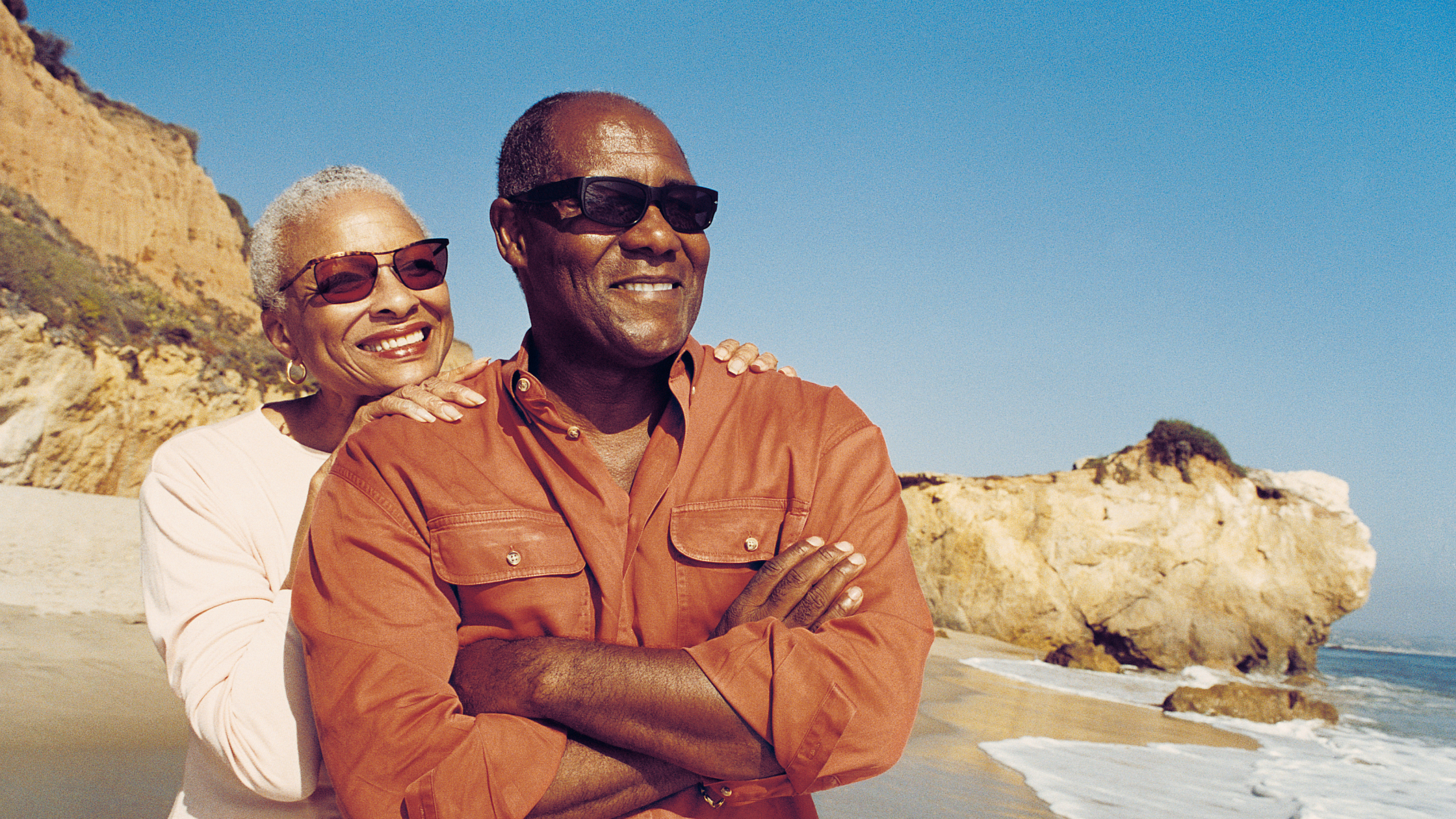 older black couple smiling on the beach
