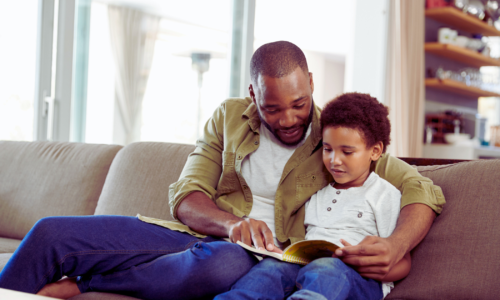black father reads a book with his son