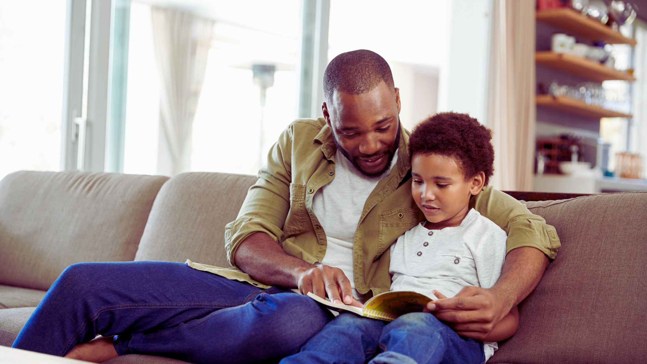 black father reads a book with his son