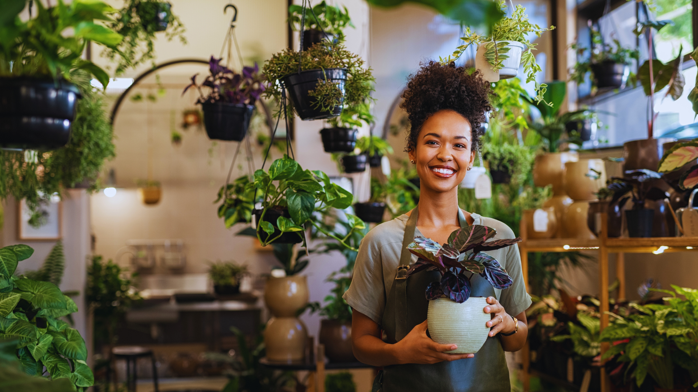 female small business owner in a plant store holding a potted plant